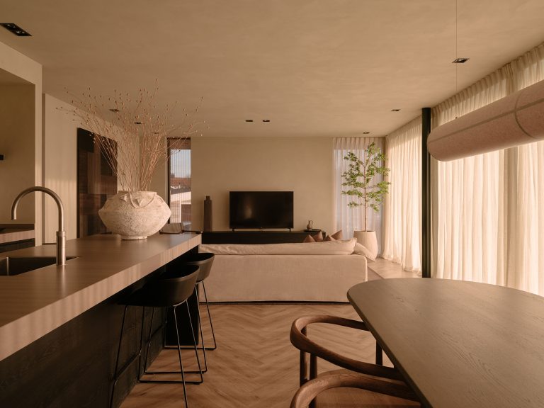 Geräumiger Wohnbereich mit offener Küche, Esstisch aus Holz, sanften Beigetönen und großen Fenstern mit Vorhängen, eingerichtet mit natürlichen Materialien und einer ruhigen, nachhaltigen Ausstrahlung