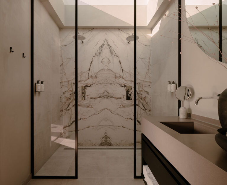 Ein stilvolles Badezimmer mit doppelter begehbarer Dusche, einer Akzentwand in Marmoroptik, klaren Linien und ruhigen Naturtönen für ein luxuriöses Wellness-Ambiente