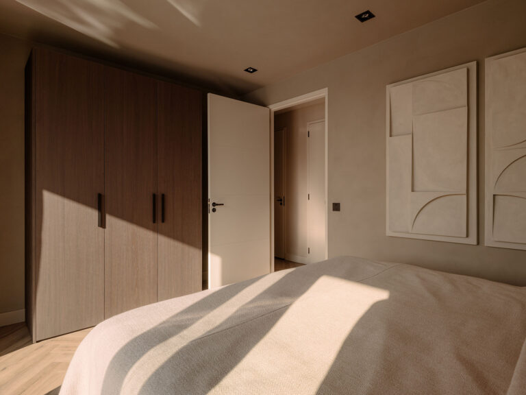 Sfeervolle slaapkamer met zacht beddengoed, houten kledingkast, subtiele wandkunst en warme lichtinval in een rustige villa setting