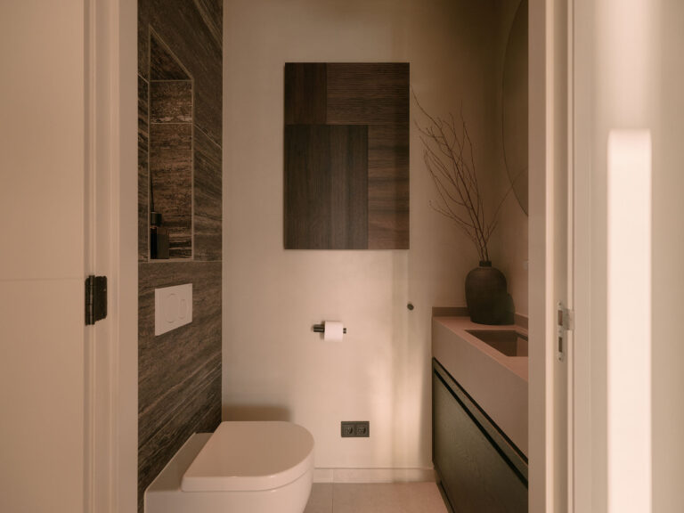 Moderne Gästetoilette mit ruhigen Erdtönen, dunkler Wandverkleidung, minimalistischem Waschbecken und raffinierten Accessoires in einer eleganten Villa